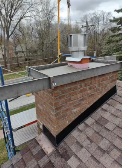 Brick chimney with scaffolding around it, a new flat crown and a stainless steel liner top